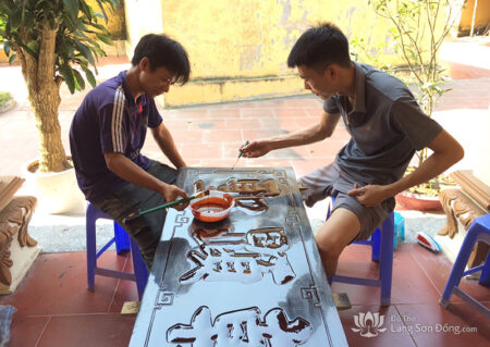 Những người thợ làng Sơn Đồng đang sơn cầm để thếp vàng, bạc cho bức hoành phi